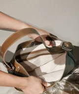 Cartera tipo lady bag color lila, de cuero sintético, con correa ajustable y herrajes metálicos plateados.