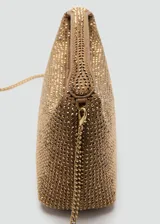 Bolso de mano tipo baguette, color dorado, completamente cubierto de pedrería brillante. Presenta un asa corta integrada y cierre superior con tirador metálico.