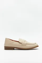 Mocasín de cuero sintético color beige, con diseño de punta cuadrada y detalle de costura decorativa en el borde superior. Cuenta con un taco bajo de 2,5 cm.
