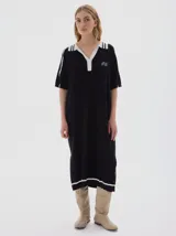 Vestido midi tejido de algodón color negro, con cuello camisero blanco, escote en V con tres botones, mangas cortas con rayas blancas y aberturas laterales.