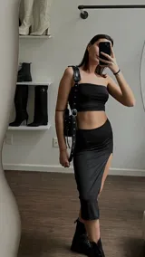 Conjunto de dos piezas color negro compuesto por un top estilo strapless corto y una falda midi con tajo lateral pronunciado.