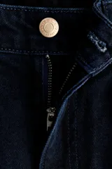 Jean de tiro alto y pierna ancha en denim de algodón negro, con diseño clásico de cinco bolsillos, cierre de cremallera y botón metálico.