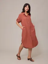 Vestido camisero largo de corte holgado, con cuello clásico, cierre frontal completo con botones y mangas tres cuartos.