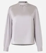 Blusa de mangas largas color gris claro, confeccionada en poliéster satinado, con cuello mao y puños abotonados.