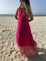 Vestido largo de fibrana fucsia con volado rosa en el ruedo y tiras finas que se atan en los hombros.