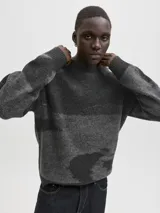 Sweater de punto con diseño de bloques de color en tonos grises y negros, manga larga, cuello redondo y ajuste relajado. Presenta puños y cuello acanalados con una textura suave y elástica.