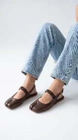 Chatitas estilo Tabi en cuero color chocolate, con diseño de punta dividida, tira elástica fruncida en el empeine y tira trasera con hebilla ajustable.