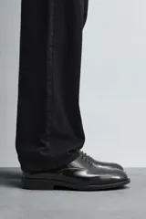 Zapato de vestir tipo derby color negro acharolado, con horma en punta y suela con ligero tacón.