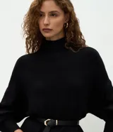 Suéter de punto de corte oversize y largo alargado, con cuello alto, mangas largas y aberturas laterales sutiles. Presenta puños y ruedo con acabado acanalado.