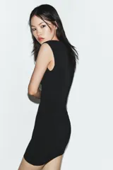 Vestido corto de punto stretch, color negro, con cuello redondo, manga sisa y detalle de abertura frontal en forma de corazón en el pecho.