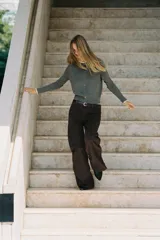 Chaqueta de punto color beige, de manga larga y corte corto, con cuello redondo y puños terminados en puntilla blanca a contraste.