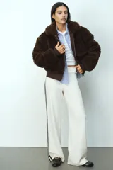 Campera corta de textura efecto peludito en color marrón oscuro. Presenta cuello alto, cierre frontal, bolsillos delanteros con solapa y puños y bajo en punto acanalado.