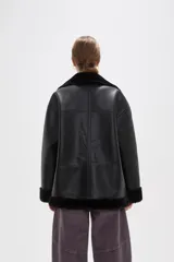 Campera de cuero sintético con interior y detalles de piel sintética en cuello, puños y ruedo. Presenta cierre frontal completo y diseño de corte holgado.