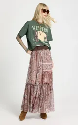 Remera de algodón color verde con estampado frontal estilo western, cuello redondo y mangas cortas. Incorpora mangas largas ajustadas de tul integradas debajo de las mangas cortas.