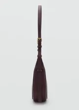 Riñonera de efecto piel color bordó, con diseño estructurado de líneas curvas, cierre de cremallera y asa ajustable con hebillas y herrajes metálicos dorados.