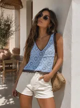 Blusa celeste de crochet con escote en V y terminaciones en color marrón oscuro.