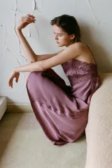 Vestido midi satinado de corte lencero, con escote en pico y tirantes finos. Presenta detalles de bordados florales y aplicaciones de encaje en la parte superior.