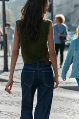 Chaleco de punto en color verde oliva, con escote en pico y sisas amplias. Presenta terminaciones acanaladas en el cuello, las sisas y el ruedo.