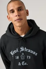 Hoodie de corte relaxed color negro, con capucha con cordón ajustable y diseño gráfico frontal con el nombre de la marca en tipografía gótica y detalles de escudo.