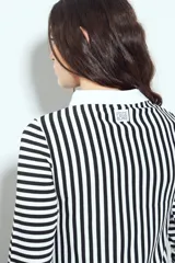 Remera de manga larga a rayas verticales verdes y blancas, con cuello polo y cierre frontal de botones. Presenta un diseño ajustado al cuerpo.