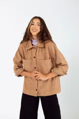 Camisa de paño marrón con estampado a cuadros, de corte oversize, cuello clásico, cierre frontal con botones, mangas largas con puños abotonados y dos bolsillos de parche en el pecho.