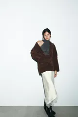 Chaqueta tipo blazer oversize de piel de ante color marrón oscuro, con cuello solapa de muescas, manga larga y bolsillos delanteros con solapa. Cierre frontal con botones.