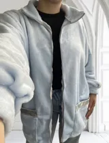Campera celeste de tela tipo peluche, con cierre frontal, cuello alto y bolsillos con ribete plateado.