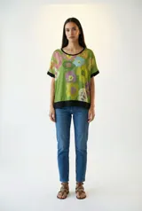 Remera poncho verde con estampado de flores y cuello redondo con ribete negro.