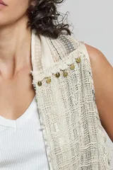 Cardigan sin mangas confeccionado en algodón con tejido texturizado y bajo asimétrico. Presenta bordes deshilachados, bordados detallados y adornos de monedas doradas a lo largo de las solapas.