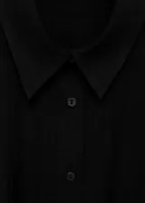 Camisa negra de manga corta con cuello camisero, cierre frontal con botones y diseño entallado con pinzas en la cintura.