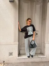 Remera oversize de algodón negro, con diseño gráfico frontal que incluye la leyenda "COFFEE CLUB" y una ilustración estilo retro de una mujer bebiendo café.