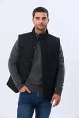 Chaleco reversible acolchado con cierre frontal de cremallera y botones a presión. Presenta cuello alto, diseño capitoneado y bolsillos laterales. Un lado está confeccionado en nylon resistente y el otro en una mezcla de algodón y poliéster.