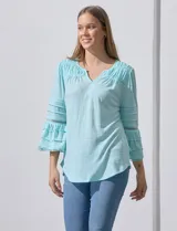 Blusa color celeste con escote en V, mangas largas acampanadas con detalle de crochet y frunces en los hombros.
