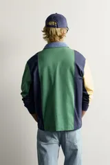 Polo de manga larga con diseño de rayas verticales anchas en colores amarillo, verde, rojo, azul marino y celeste. Cuenta con cuello camisero de denim y cierre frontal parcial con botones ocultos bajo solapa.