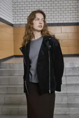 Chaqueta tipo biker de gamuza sintética negra, con cuello solapa, cierre frontal asimétrico y bolsillos con cierre.