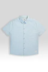 Camisa de manga corta celeste con rayas verticales blancas, cuello clásico, cierre frontal con botones y bolsillo de parche en el pecho.