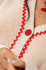 Saco oversize tejido con ilustraciones inspiradas en corales, peces, estrellas de mar y tortugas. Presenta galón picot en rojo en cartera y puños, y botones a tono.