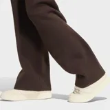 Pantalón de punto Adidas Essentials de color marrón, con diseño holgado y el emblemático logo del Trifolio bordado en blanco en la pierna izquierda.