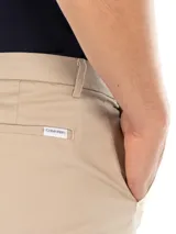 Pantalón de vestir de corte slim, color beige, confeccionado en mezcla de algodón elástico. Presenta cierre de botón y cremallera.