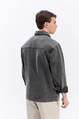 Campera de jean de corte recto y lavado desgastado, con cuello clásico, cierre frontal con botones metálicos y un bolsillo grande aplicado en el pecho.