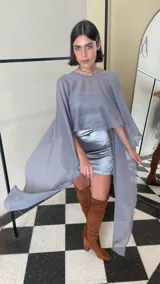 Vestido corto de dos piezas compuesto por una base strapless con frunces y acabado satinado, acompañada de una capa transparente desmontable de corte asimétrico.