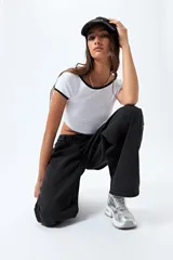 Top corto negro de punto acanalado con escote redondo, mangas cortas y ribetes blancos en cuello y mangas.