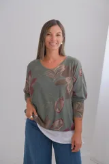 Sweater de punto amplio con diseño de flores estampadas en tonos verdes y rojizos, escote en V y mangas largas. Presenta un diseño de doble capa con un borde inferior en color blanco.