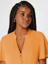 Blusa color naranja con escote en V y botones frontales. Manga corta.