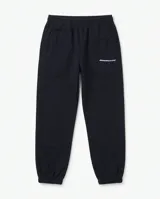 Pantalón de jogging negro de algodón premium, con cintura elástica, bolsillos laterales y puños elastizados en los tobillos. Presenta pequeño estampado tipográfico en la pierna izquierda.