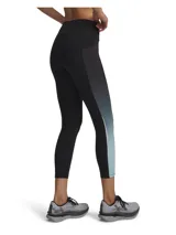 Calza deportiva de corte tobillero con tecnología HeatGear, diseñada para ofrecer alta transpirabilidad y secado rápido. Presenta un diseño bicolor con paneles laterales en degradado de gris a celeste, cintura elástica de tiro alto con cordón interno, bolsillos laterales y detalles reflectantes.