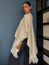 Ruana tejida a mano en punto arroz con lana merino, presenta un diseño envolvente con flecos en los extremos.