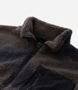 Campera de sherpa con estampado camuflado en tonos marrones y grises, de corte oversize y manga larga. Presenta cuello alto, cierre frontal completo y un bolsillo frontal contrastante en color negro con cierre.