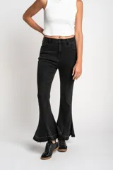 Pantalón de jean negro con corte flare, tiro medio y ruedo desflecado.