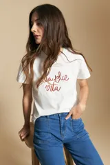 Remera de manga corta color marrón, con la frase "la dolce vita" bordada en azul en el frente y mangas con dobladillo.